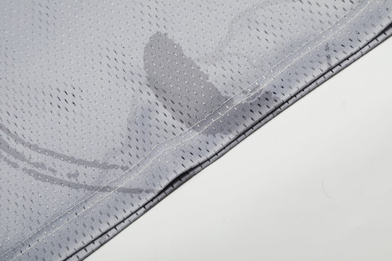 Close-up of gray mesh football jersey fabric with stitched hem and subtle portrait graphic pattern