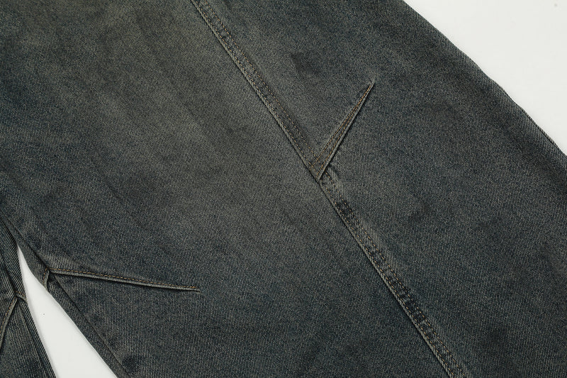Close-up of curved seam detail on dark wash denim pant leg