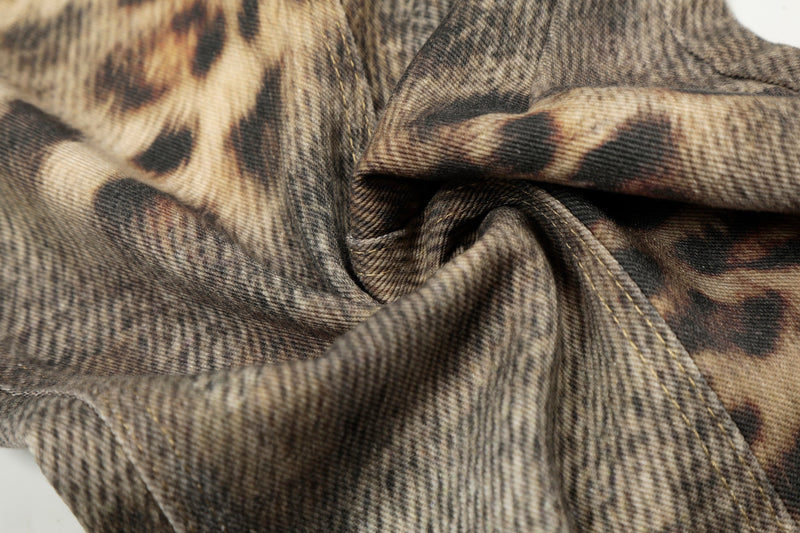 Close-up of crinkled leopard wash denim fabric with stitched seams