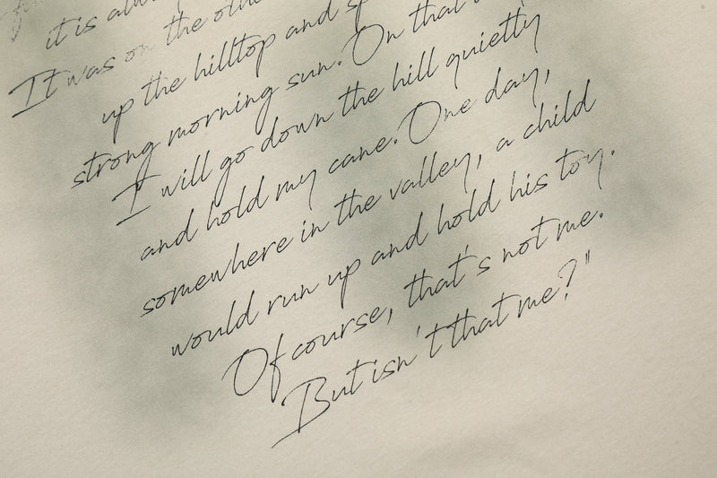 Close-up of a washed vintage tee graphic with diagonal handwritten script on a cream fabric background
