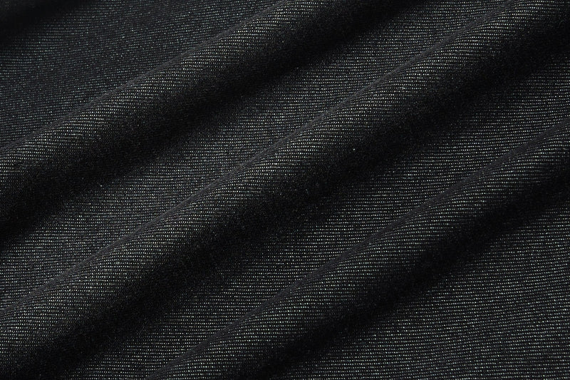 Close-up of black denim fabric with subtle texture and diagonal folds for a streetwear button-up shirt