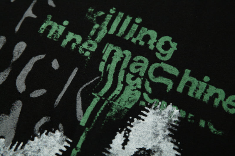 Close-up of a black graphic patchwork crop tee with distressed green lettering and white abstract print accents