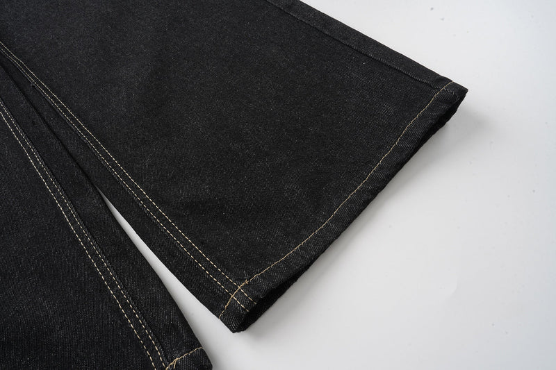 Wide-leg black jeans leg close-up with stitched hem