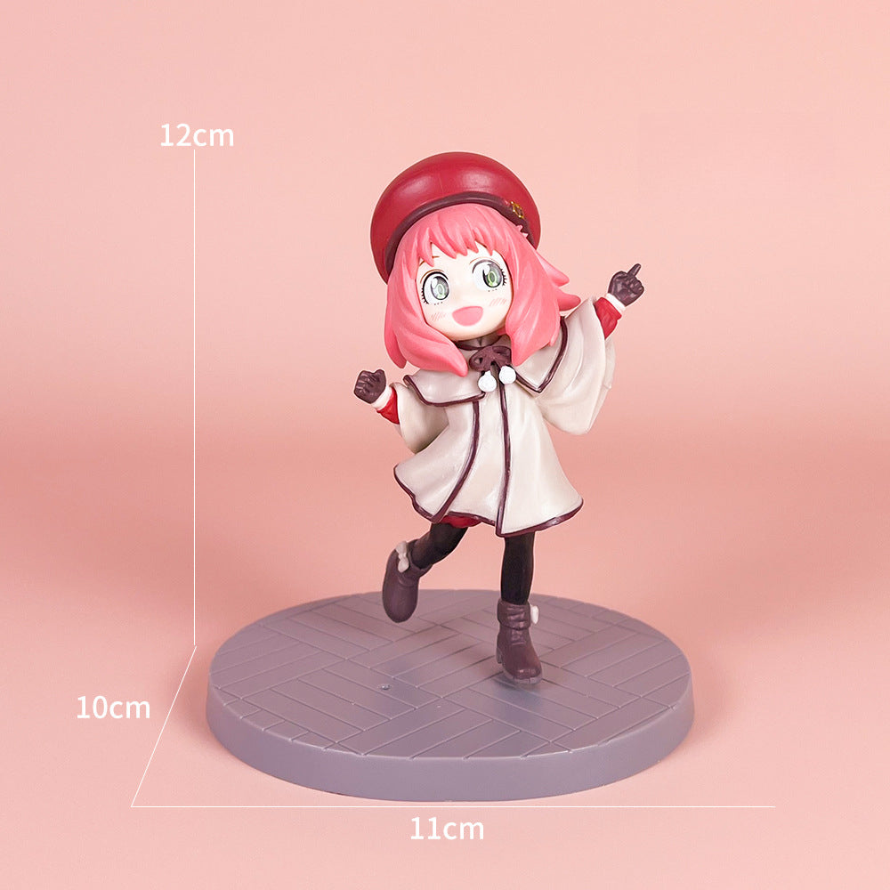 The Spy x Family Detective Anya PVC Figure Set depicts a smiling pink-haired girl with a red beret, white coat, and black leggings. Standing on a round gray base, the figure is 14 cm tall and part of the movie version offering four poses.