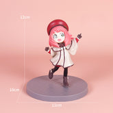 The Spy x Family Detective Anya PVC Figure Set depicts a smiling pink-haired girl with a red beret, white coat, and black leggings. Standing on a round gray base, the figure is 14 cm tall and part of the movie version offering four poses.