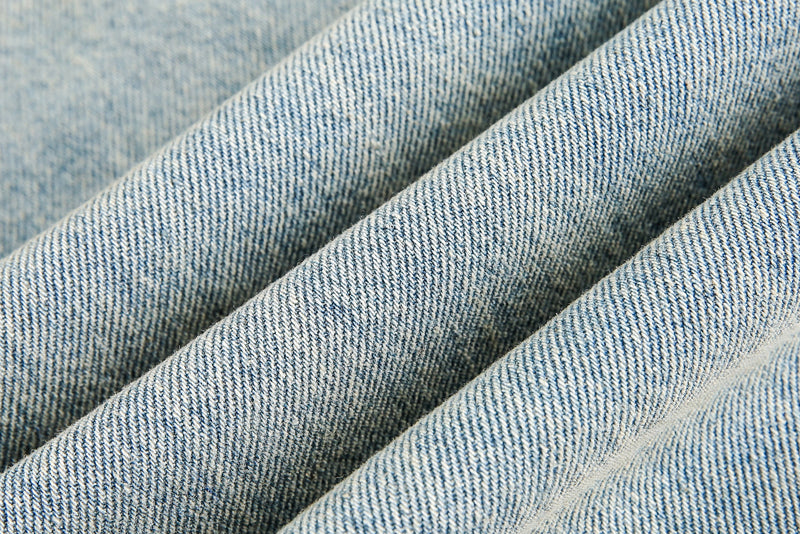 Close-up of folded light blue denim fabric showing heavy texture and faded wash