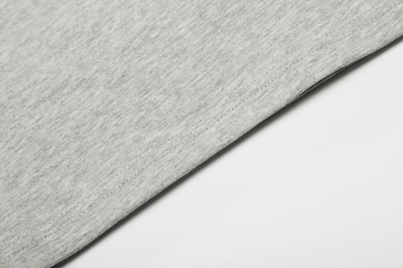 Close-up of light gray heathered cotton fabric with a clean hem on a minimalist white background
