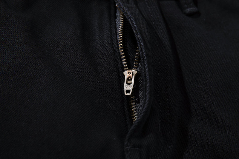 Close-up of black YKK zipper on the front of denim pants