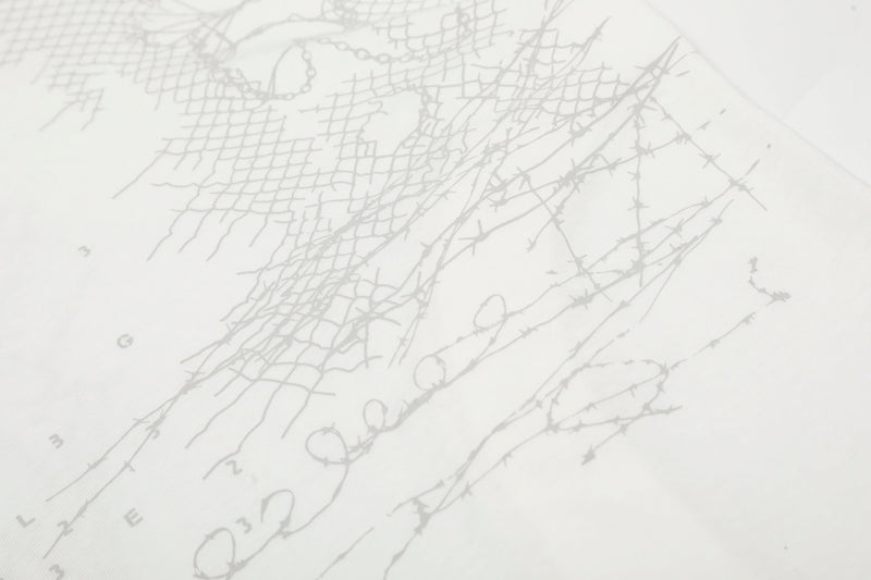 Close-up of white tee front graphic with cracked-line pattern and faint lettering