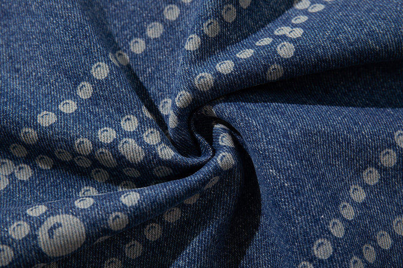 Close-up of blue denim fabric with white dot pattern and soft folds