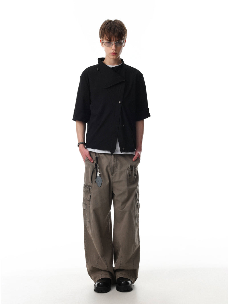 Model wearing a black asymmetrical stand-collar cotton shirt with short sleeves and minimalist streetwear styling