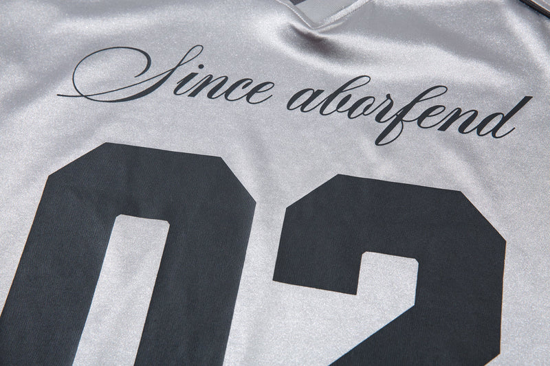 Close-up of front chest graphic reading Since aborfend above 02 on light gray jersey