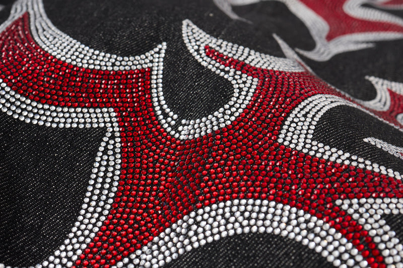 Close-up of red and silver rhinestone flame graphic on black denim fabric