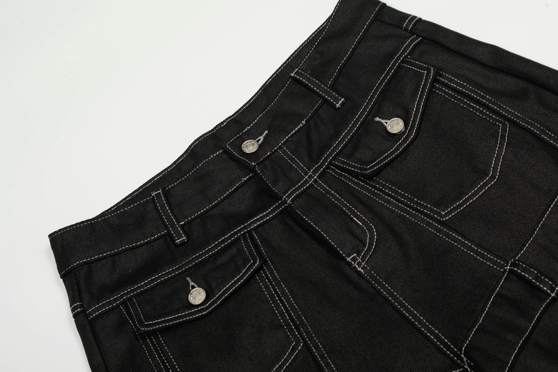Close-up of the waistband and front pockets on black denim pants with contrast stitching