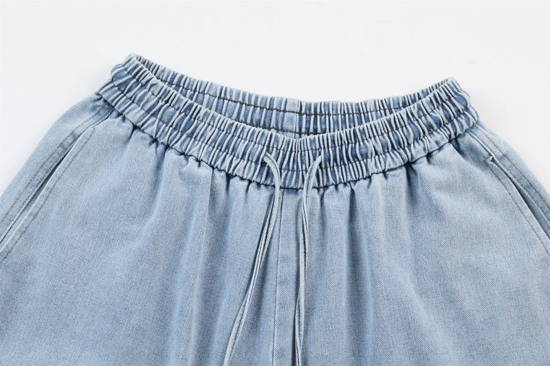 Close-up of light wash denim elastic waistband with gathered pleats and drawstring detail
