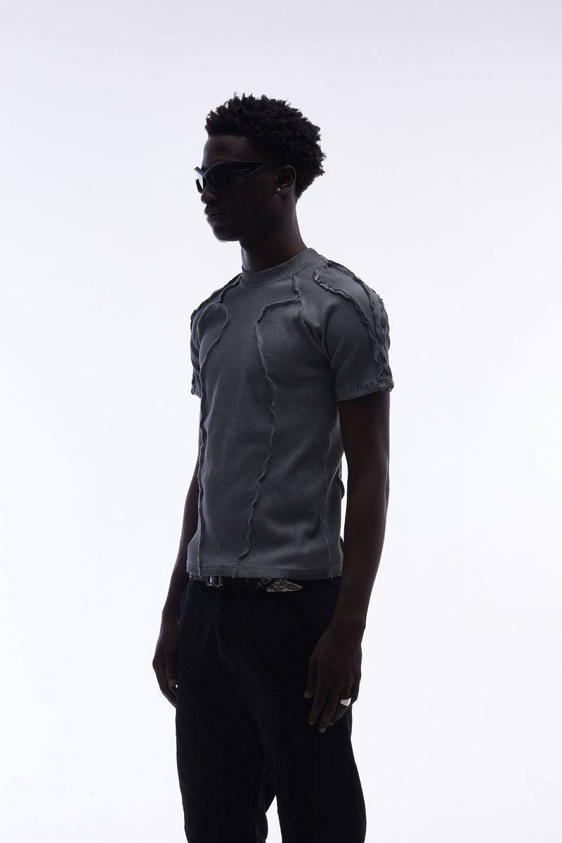 Model wearing a gray raw seam compression tee with deconstructed stitching and a fitted streetwear silhouette