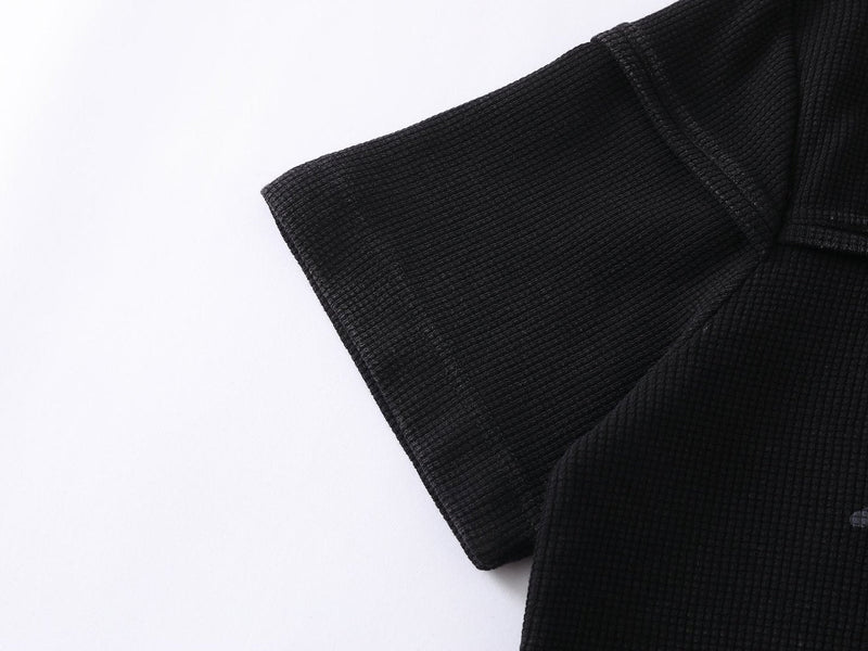 Black waffle knit streetwear T-shirt sleeve detail with textured fabric and script logo accent