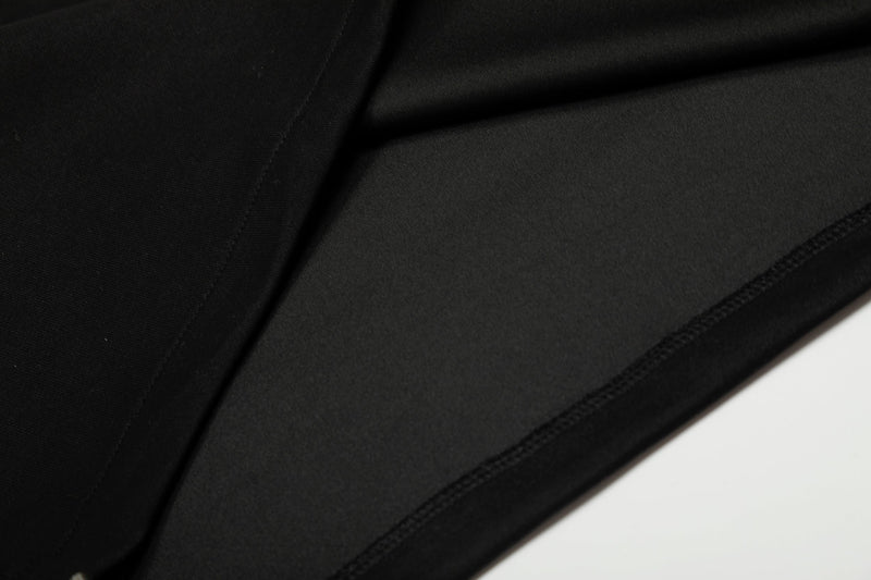 Black sweatshirt fabric close-up showing smooth knit texture and seam stitching