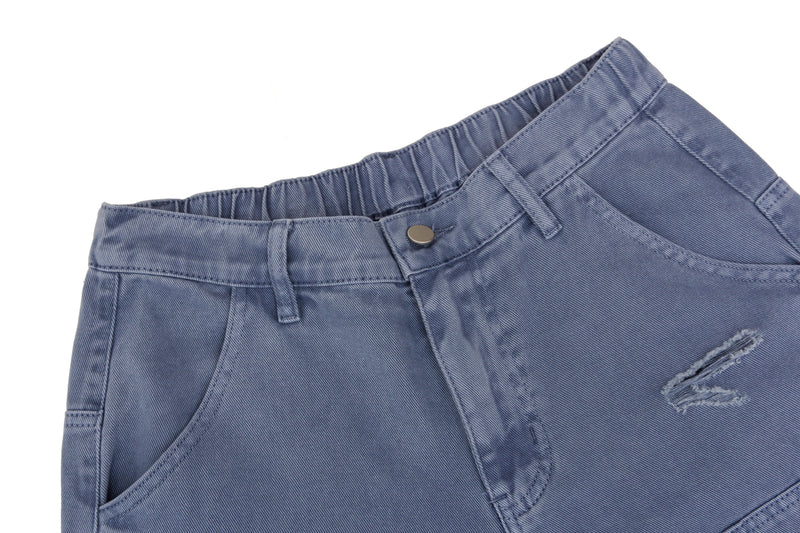 Close-up of the waistband and front pocket on blue distressed denim jeans