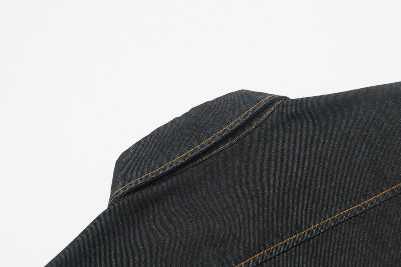 Close-up of dark denim shirt shoulder with contrast stitching and button-up seam detail