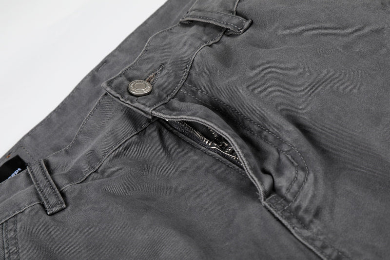 Close-up of gray cargo shorts front pocket with visible zipper opening and button flap