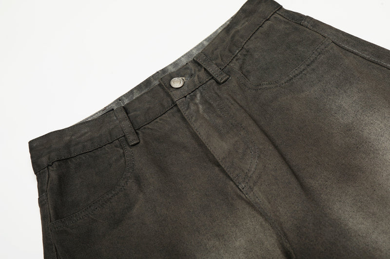 Close-up of front waistband on faded black denim pants with button closure and belt loops