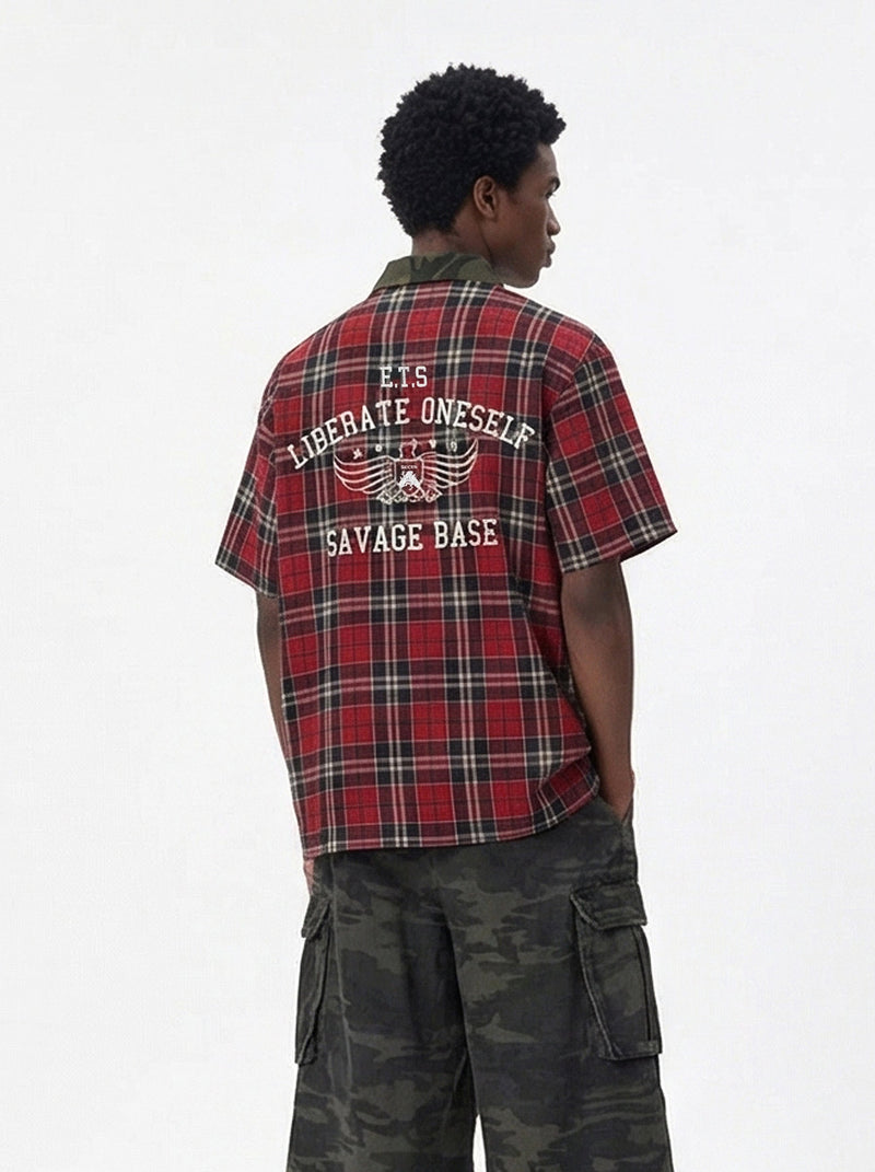 Red plaid short-sleeve shirt with camo collar and bold back graphic, styled with dark camo cargo pants
