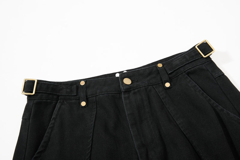 Close-up of black pants waistband with gold buckle belt loop and snap details