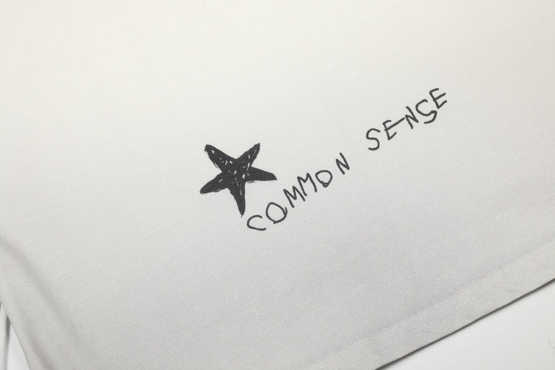 Close-up of star graphic and handwritten text on cream tee
