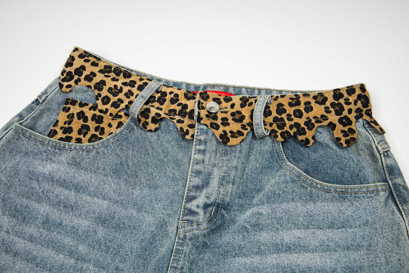Close-up of the front waistband, button fly, and leopard print trim on denim shorts