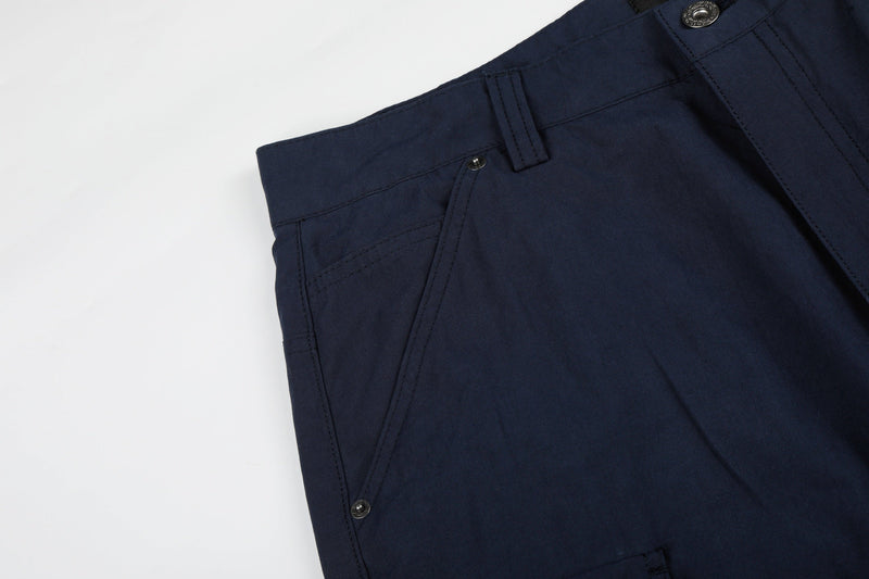 Close-up of navy cargo pants front pocket area with seam and snap details