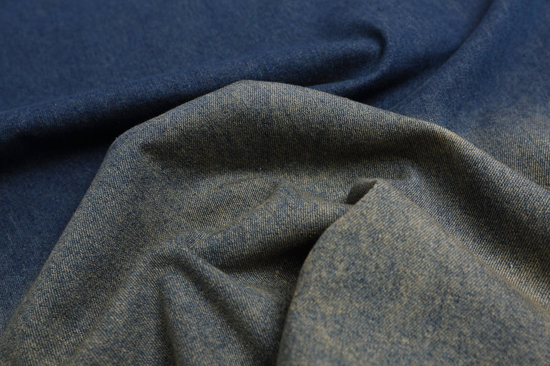 Close-up of blue denim jersey fabric with soft folds and a vintage washed texture