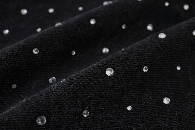 Macro close-up of black denim fabric with clear rhinestone studs