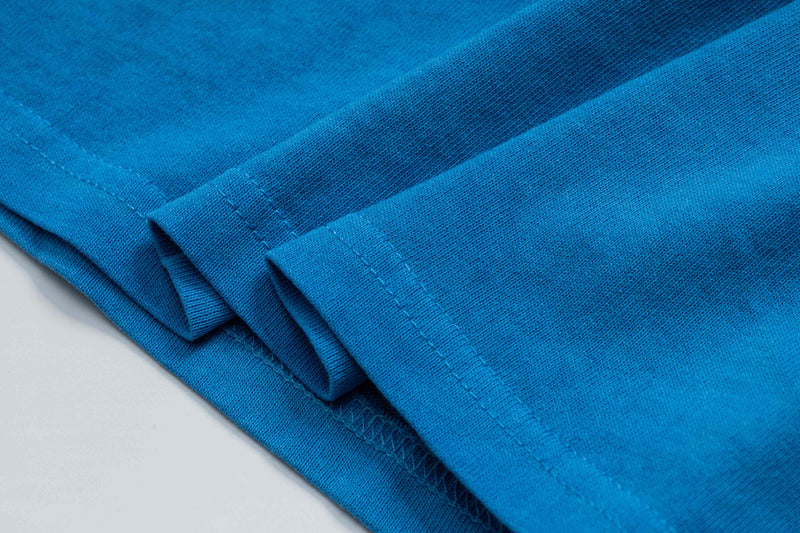 Close-up of folded blue cotton T-shirt fabric with visible stitching and vintage wash texture
