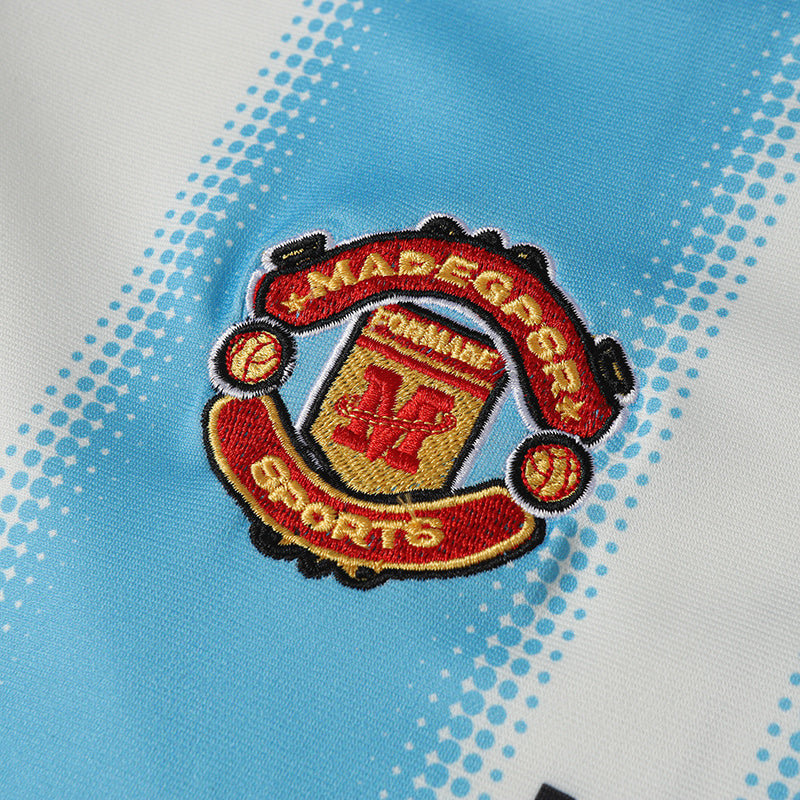 Close-up of a light blue and white striped football jersey featuring an embroidered club-style crest badge.