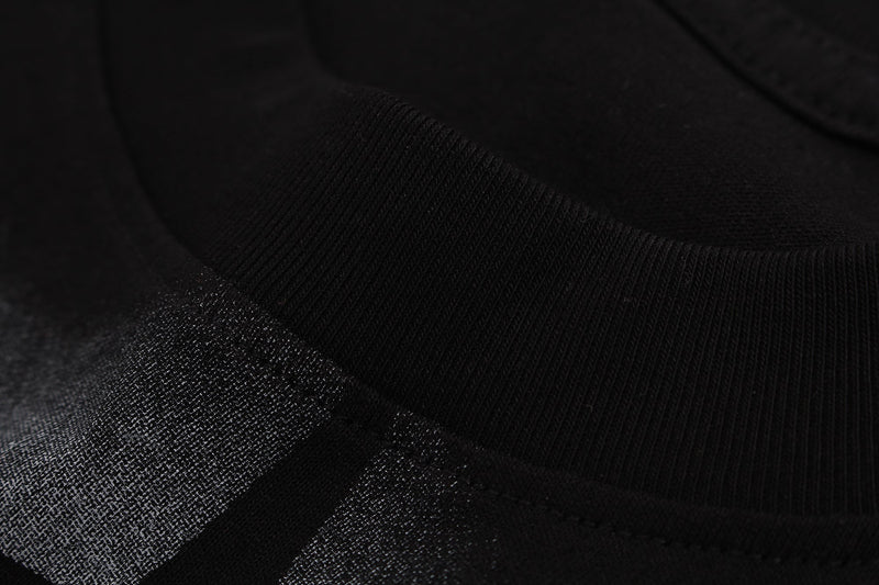 Black graphic T-shirt close-up with textured airbrush-style print and ribbed fabric detail