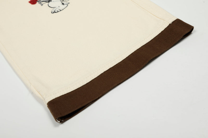 Close-up of cream pants cuff with brown hem trim