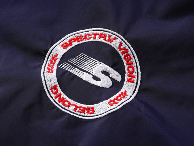 Close-up of circular Spectravision logo patch on navy nylon pullover