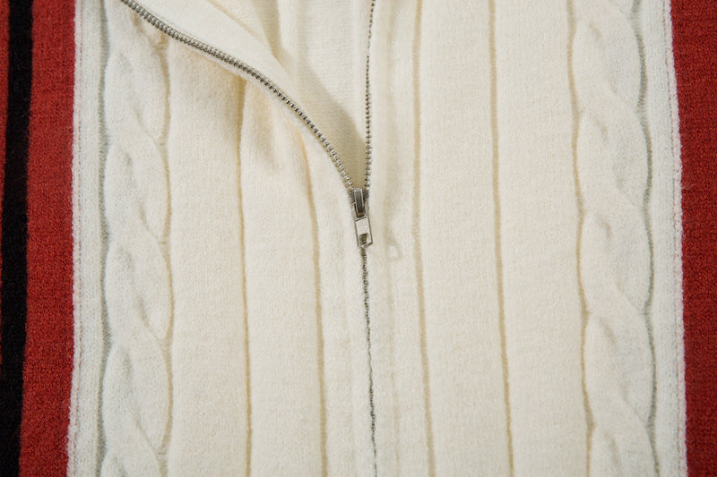 Close-up of front zipper on cream cable-knit jacket with red stripe panels