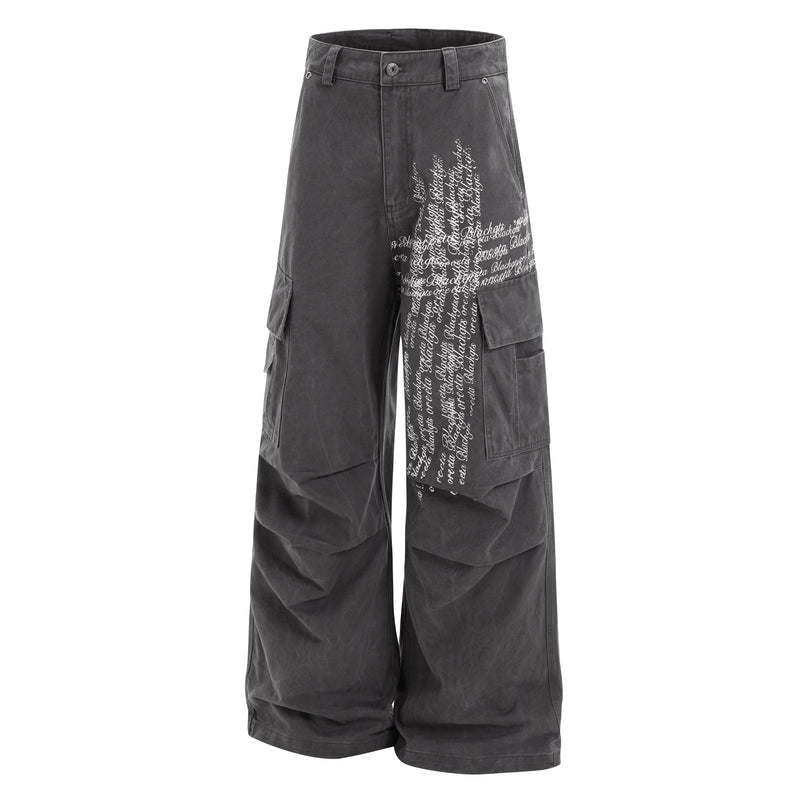 Front view of black cargo pants with white cross script print and flap side pockets
