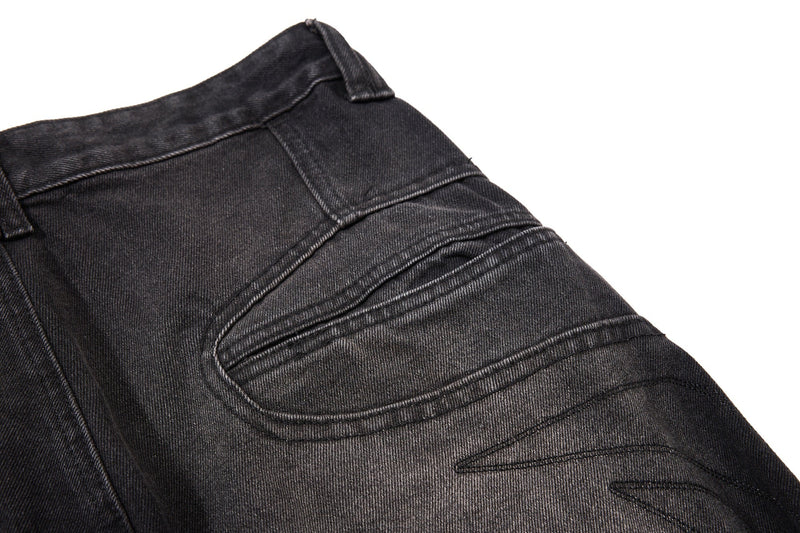 Close-up of black denim back pocket panel with curved stitched seams