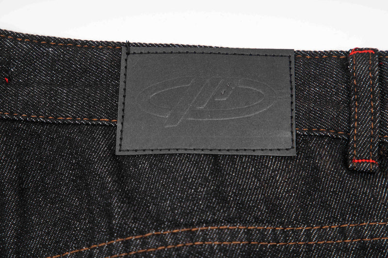 Back waistband close-up with black logo patch on dark wash denim pants