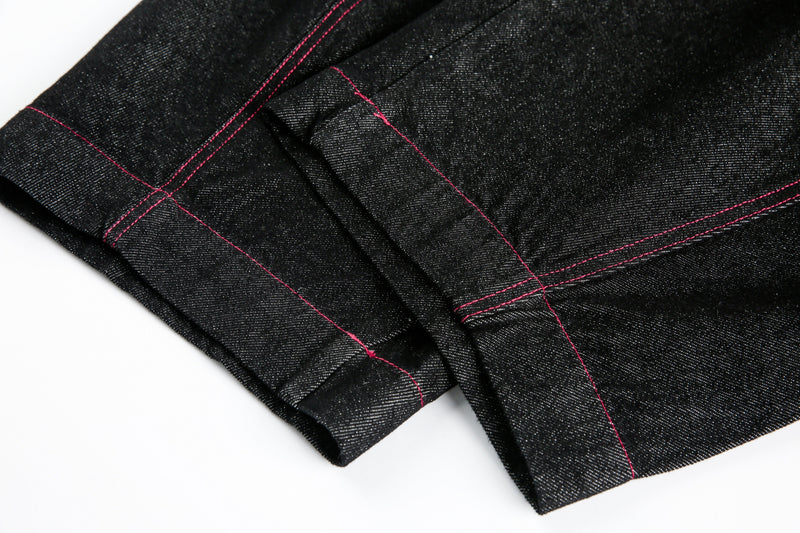 Close-up of black denim cuff and seam with red stitching
