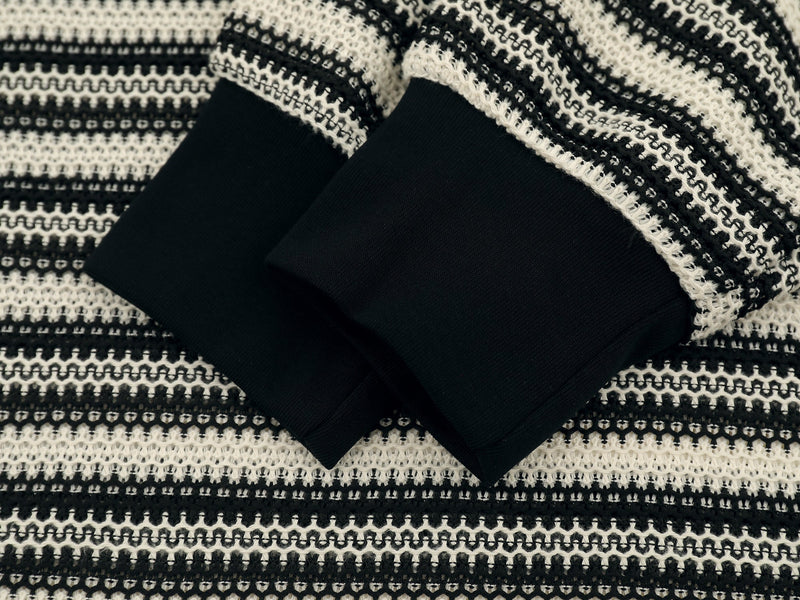 Close-up of black ribbed sleeve cuffs on a black and cream striped knit polo