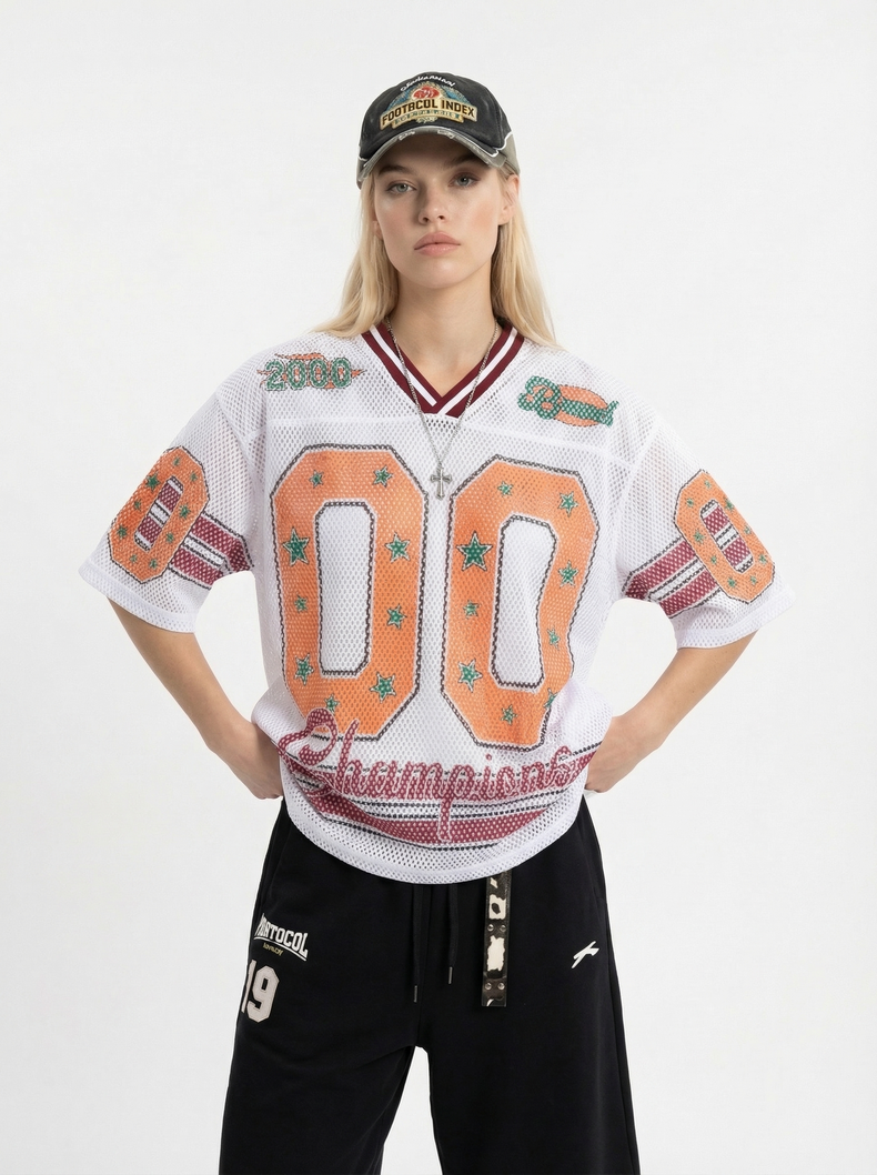 Model wearing a white mesh jersey T-shirt with orange 00 graphics, retro football details, and black streetwear pants