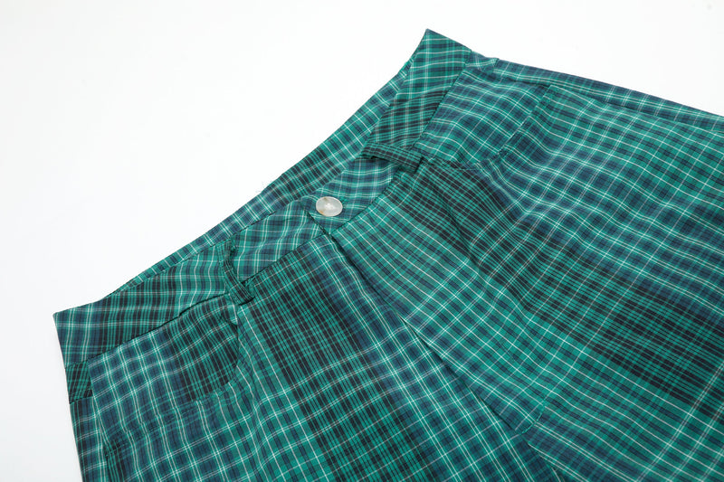 Close-up of green plaid shorts waistband and front button