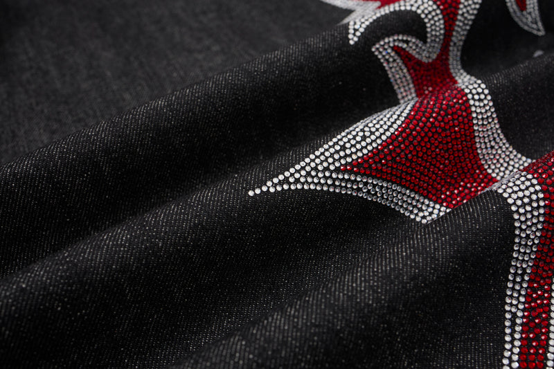 Close-up of black denim fabric with red and silver rhinestone flame accent