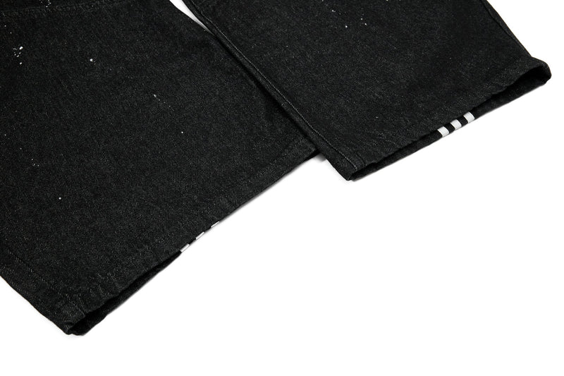 Cuffed hem of black jeans with white side stripes peeking out