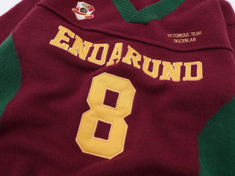 Close-up of burgundy knit sweater front showing ENDARUND lettering, number 8, and embroidered chest patch