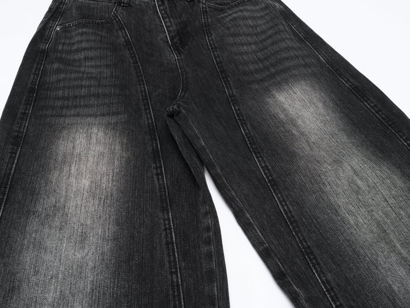 Front upper legs of black curved-leg jeans with faded wash and wide fit